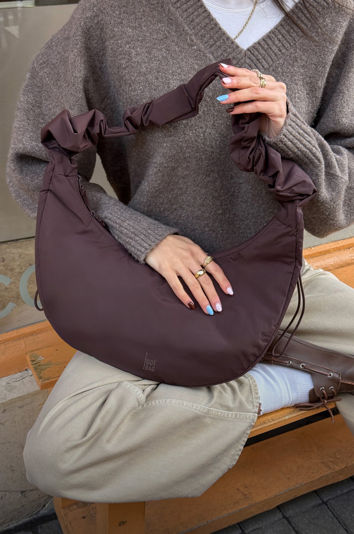MOON BAG RUFFLE tas in sea lion (donker chocoladebruin) op schoot gehouden door een vrouw.