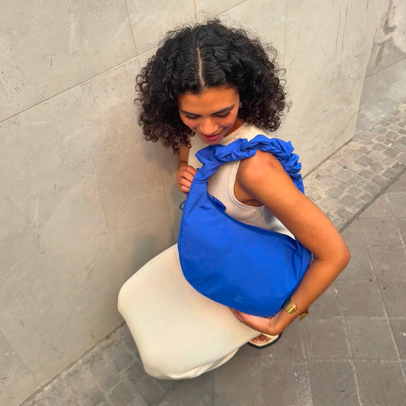 MOON BAG RUFFLE tas in cobalt (Helder kobaltblauw) door een vrouw over de schouder gedragen.