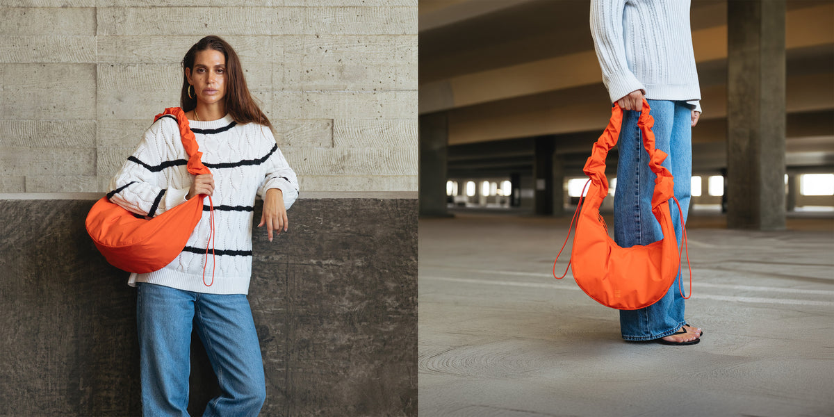 MOON BAG RUFFLE Tas in hot coral (fel oranje) over de schouder gedragen door een vrouw.
