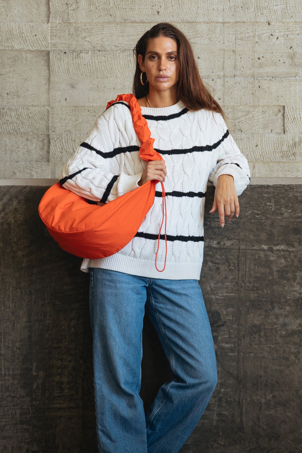 MOON BAG RUFFLE Tas in hot coral (fel oranje) over de schouder gedragen door een vrouw.