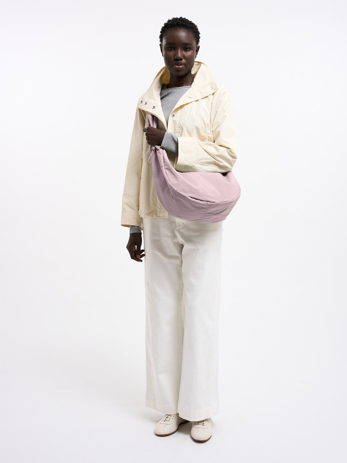 MOON BAG RUFFLE Tasche in pink dolphin (blasses Hellrosa) von einer Frau über der Schulter getragen.