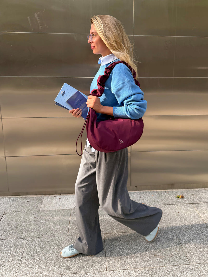 MOON BAG RUFFLE taška v kraken (burgundské) nošena přes rameno ženou.