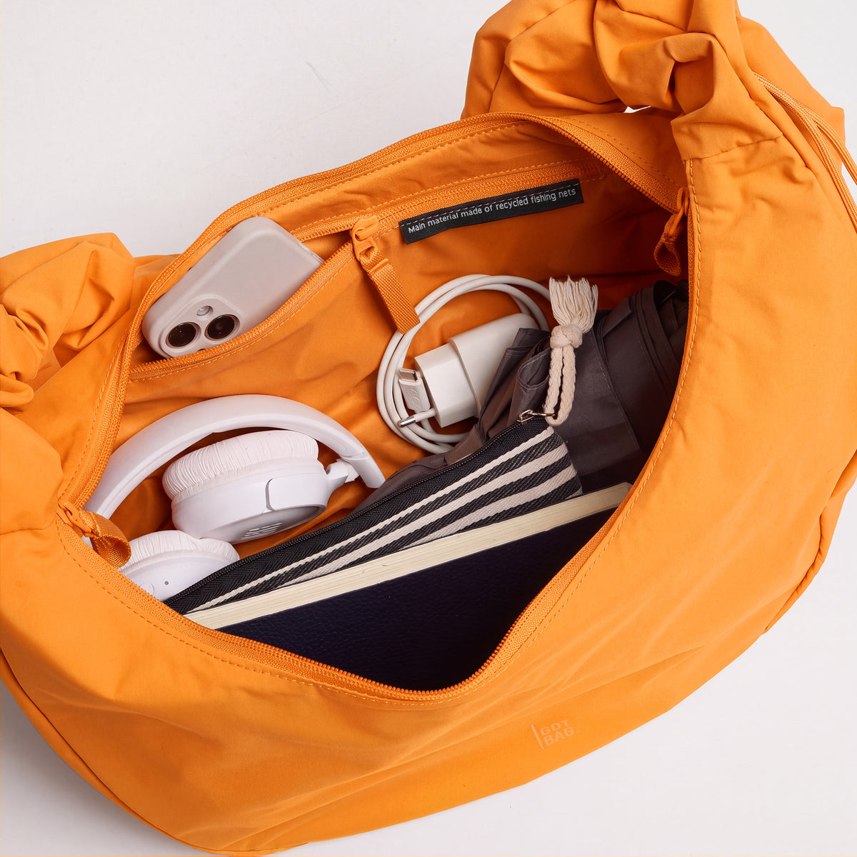 MOON BAG RUFFLE Tasche in clownfish (leuchtendes Orange-Gelb) mit Inhalt und Materialetikett.
