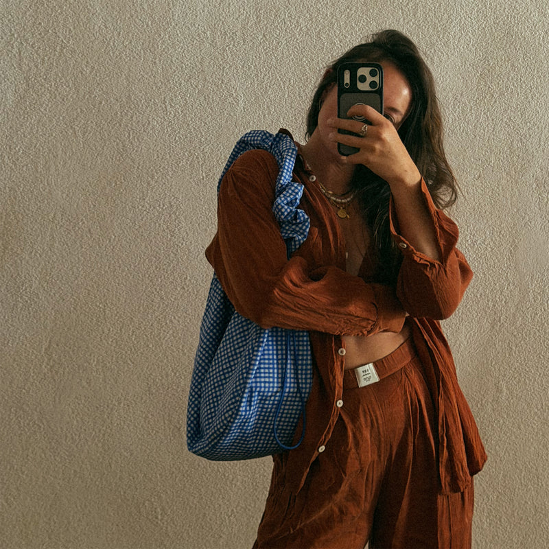 MOON BAG RUFFLE tas in vichy cobalt (Blauw-beige geruit) over de schouder gedragen door een vrouw.