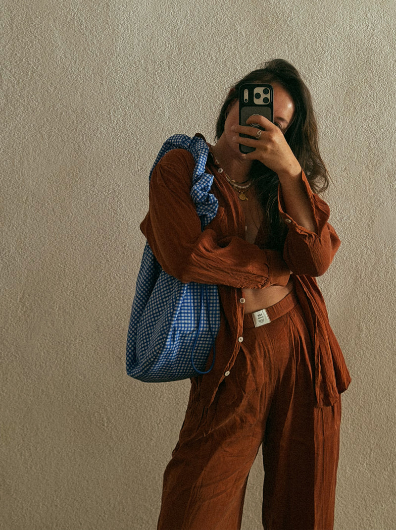 MOON BAG RUFFLE Tas in vichy cobalt (Blauw-beige geruit) gedragen over de schouder door een vrouw.