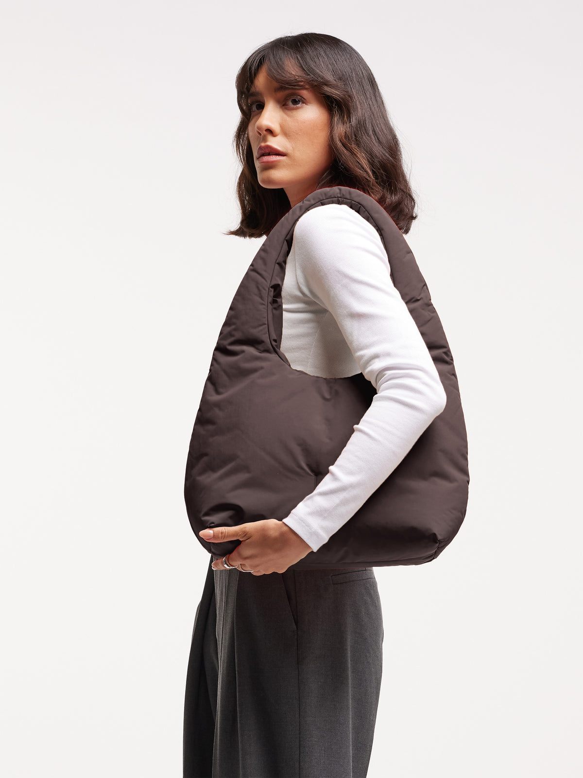 CLOUD SHOULDER BAG Tasche in sea lion (dunkles Schokobraun) von einer Frau über der Schulter getragen.