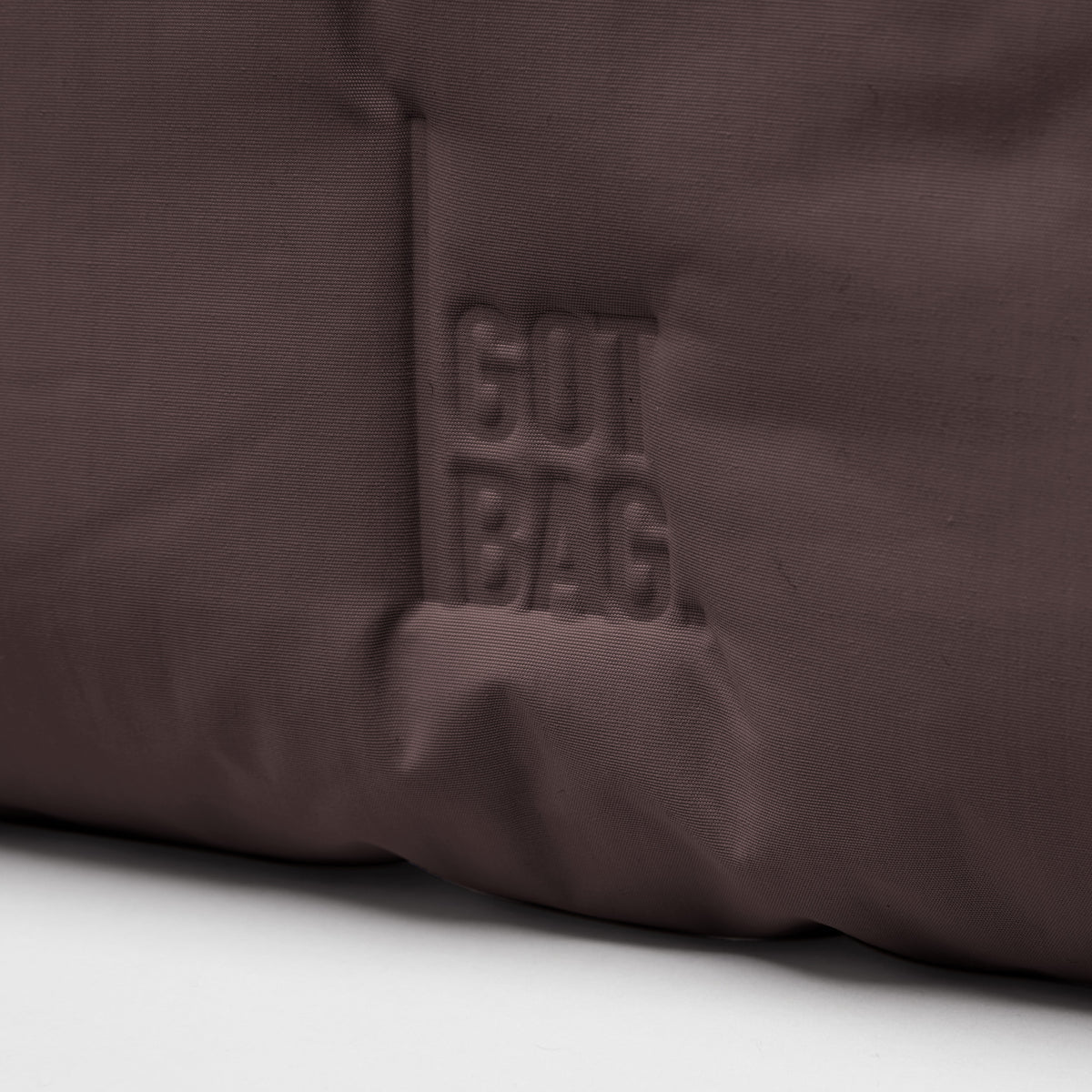 CLOUD SHOULDER BAG Tasche in sea lion (dunkles Schokobraun), Detailaufnahme mit geprägtem Logo.
