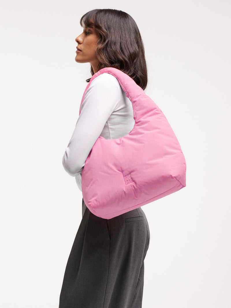 CLOUD SHOULDER BAG Tasche in sea rose (sattes Pastell-Rosa) von einer Frau über der Schulter getragen.