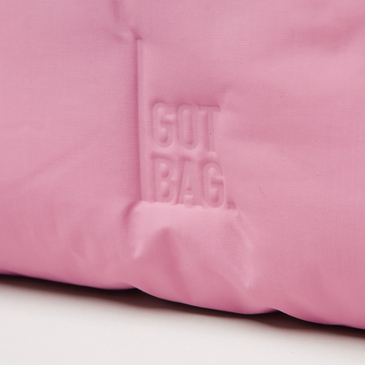 CLOUD SHOULDER BAG Tasche in sea rose (sattes Pastell-Rosa) mit geprägtem Logo als Detailaufnahme.