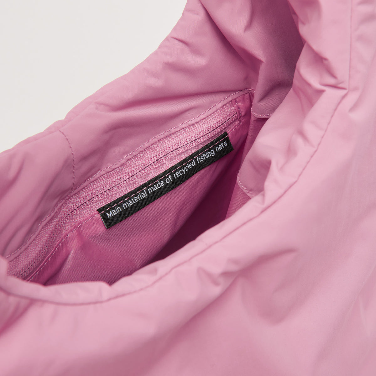 CLOUD SHOULDER BAG Tasche in sea rose (sattes Pastell-Rosa), Detailaufnahme mit Nachhaltigkeits-Etikett.