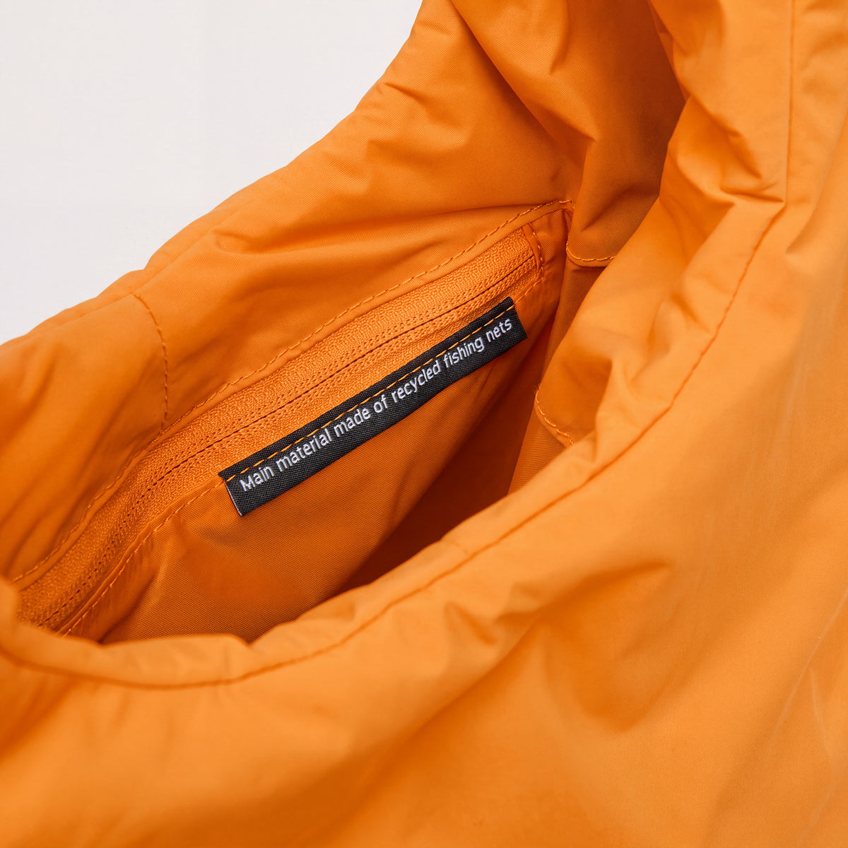 CLOUD SHOULDER BAG Tasche in clownfish (leuchtendes Orange-Gelb), Detailaufnahme innen mit Reißverschluss und Label.