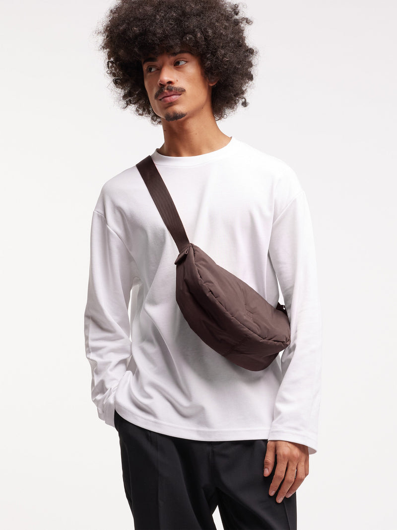 CLOUD MOON BAG SMALL Tasche in sea lion (dunkles Schokobraun) von einem Mann getragen.