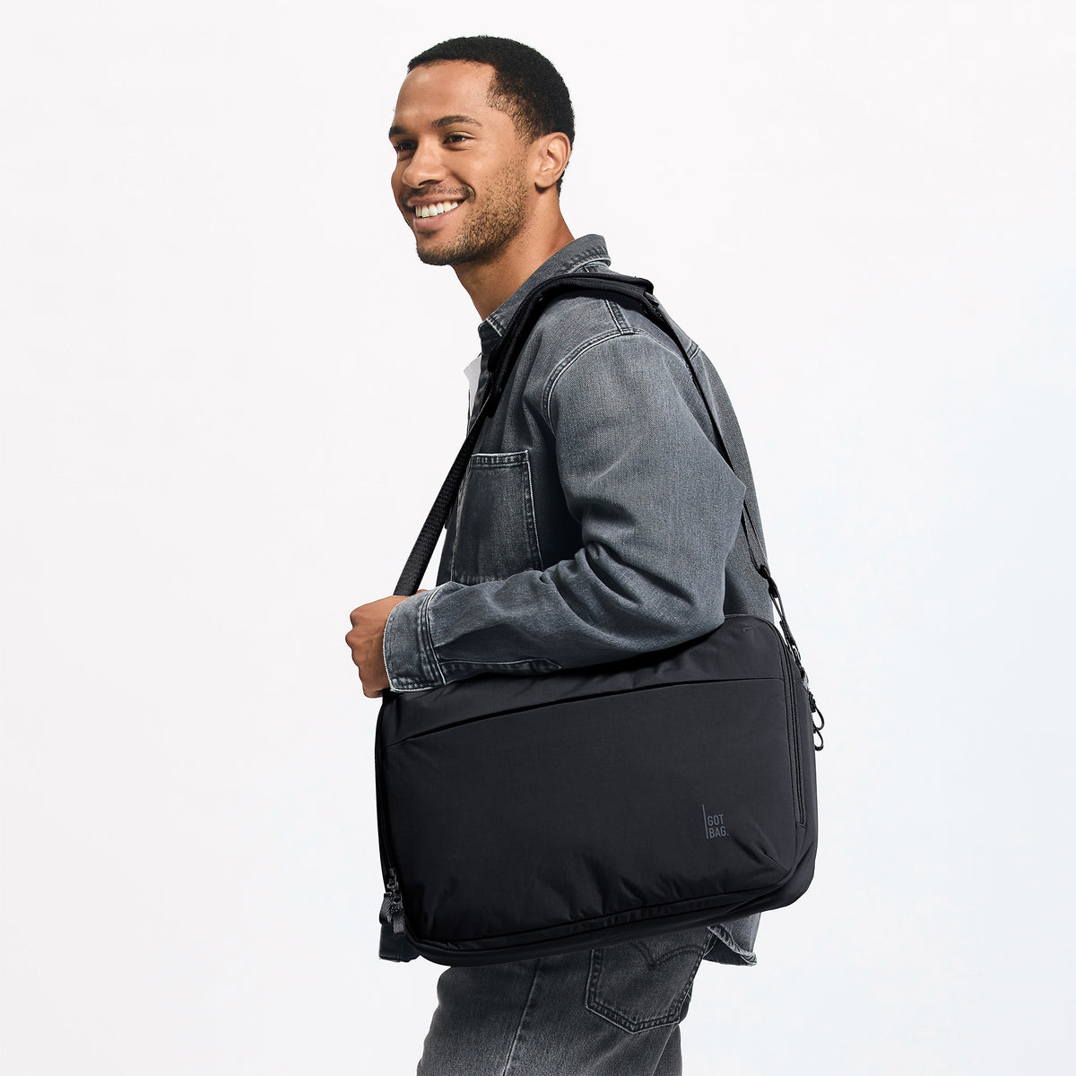 COMMUTER BAG Tasche in black (Schwarz) von einem Mann über der Schulter getragen.