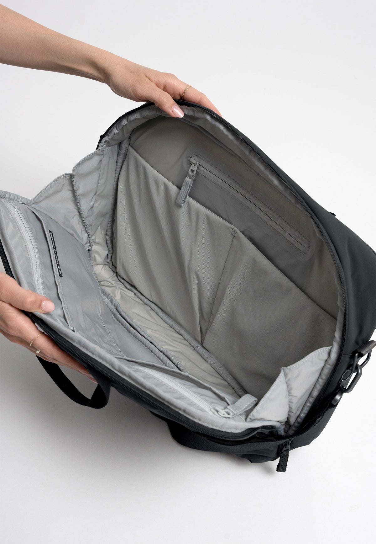 COMMUTER BAG Tasche in black (Schwarz) Detailaufnahme, von einer Frau geöffnet und gehalten.