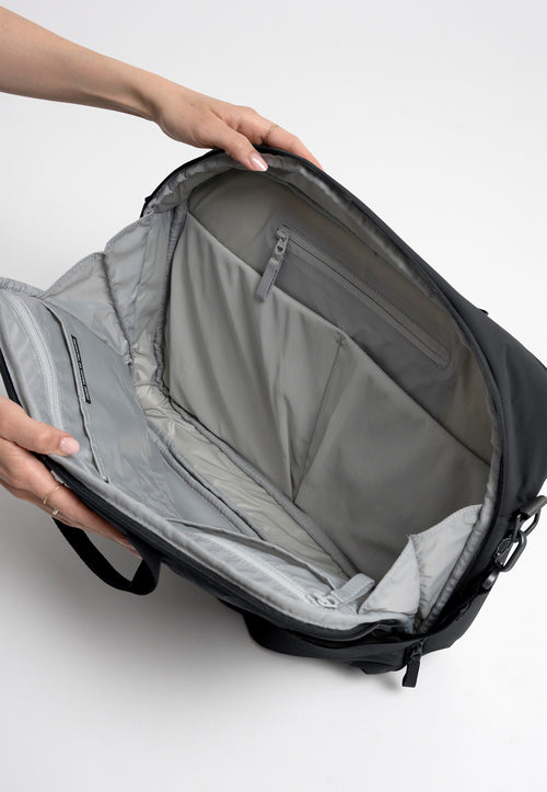 COMMUTER BAG Tasche in black (Schwarz) Detailaufnahme, von einer Frau geöffnet und gehalten.