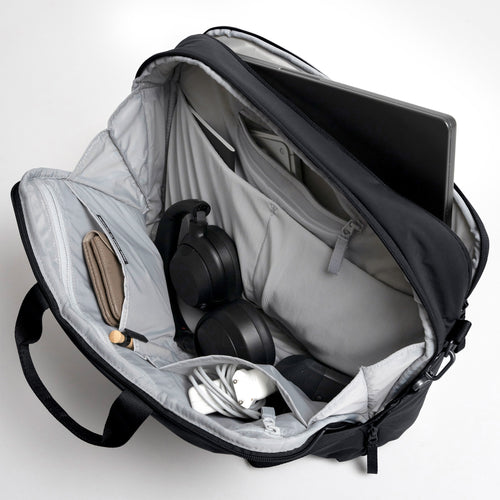 COMMUTER BAG Tasche in black (Schwarz), offene Innenansicht mit Laptop, Kopfhörern, Geldbörse und Zubehör.