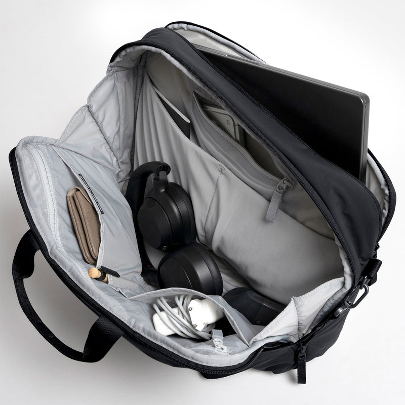 COMMUTER BAG Tasche in black (Schwarz), offene Innenansicht mit Laptop, Kopfhörern, Geldbörse und Zubehör.