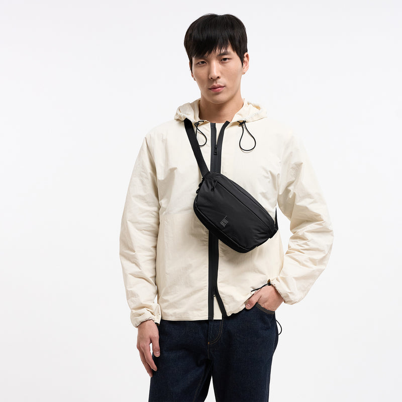ADAPT SLING BAG Tasche in black (Schwarz) von einem Mann crossbody getragen.