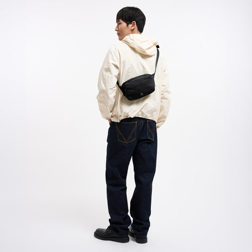 ADAPT SLING BAG Tasche in black (Schwarz) von einem Mann crossbody getragen.