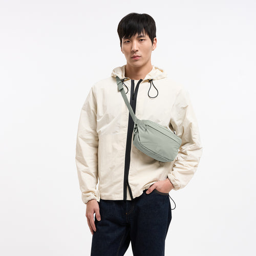 ADAPT SLING BAG Tasche in bass (Salbeigrün) von einem Mann crossbody getragen.