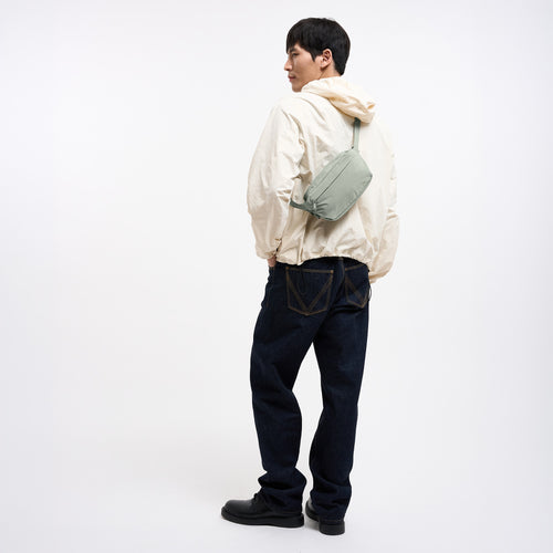 ADAPT SLING BAG Tasche in bass (Salbeigrün) von einem Mann crossbody getragen.