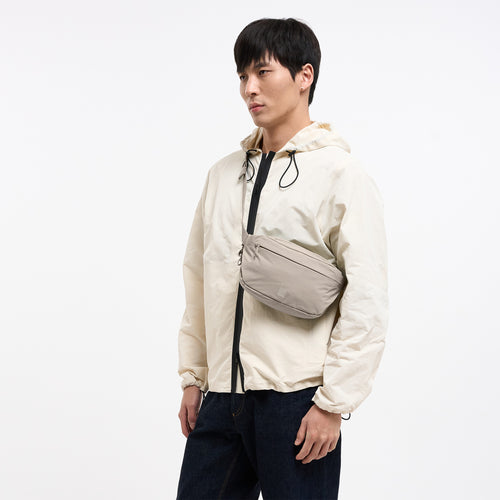 ADAPT SLING BAG Tasche in scallop (helles Beige) von einem Mann crossbody getragen.