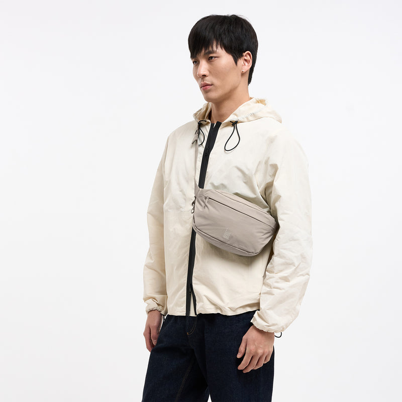 ADAPT SLING BAG Tasche in scallop (helles Beige) von einem Mann crossbody getragen.