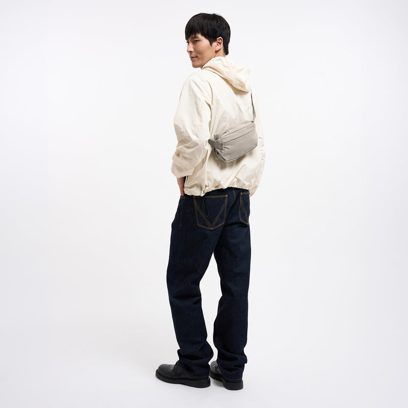 ADAPT SLING BAG Tasche in scallop (helles Beige) von einem Mann crossbody getragen.