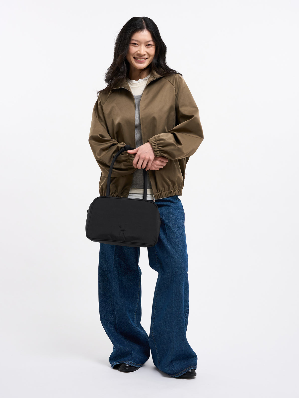 STRIKE BAG Tasche in black (Schwarz) von einer Frau in der Hand gehalten.