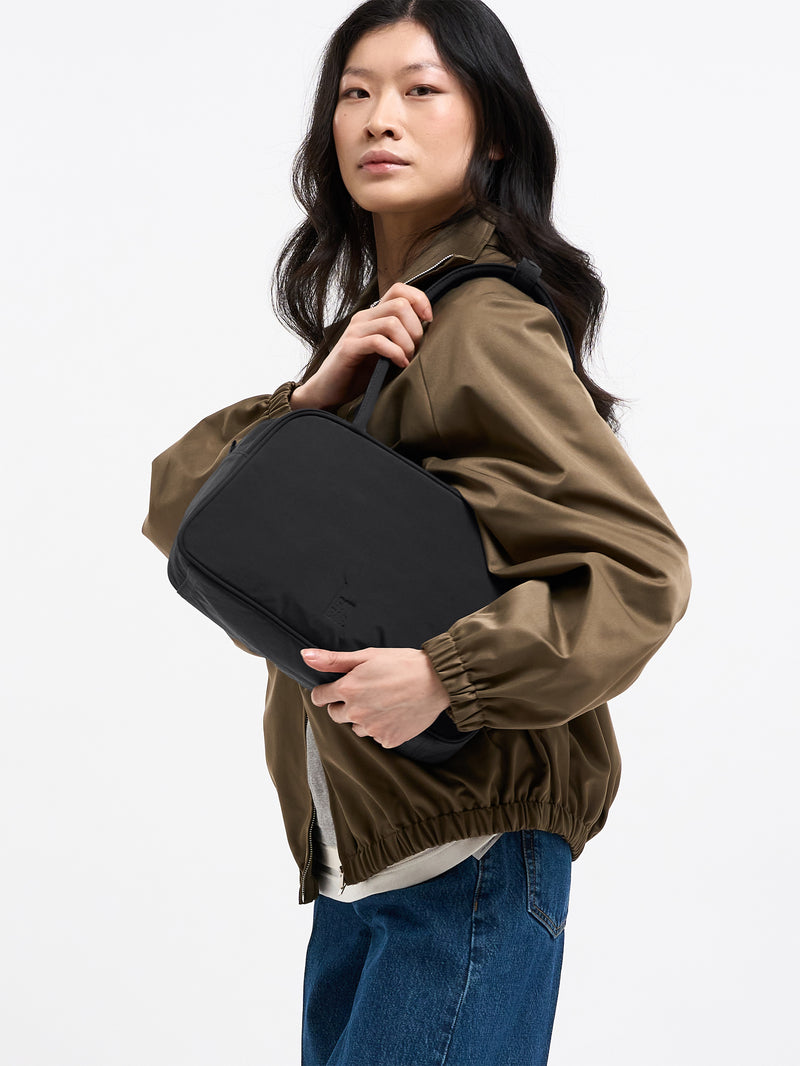 STRIKE BAG Tasche in black (Schwarz) von einer Frau über der Schulter getragen.