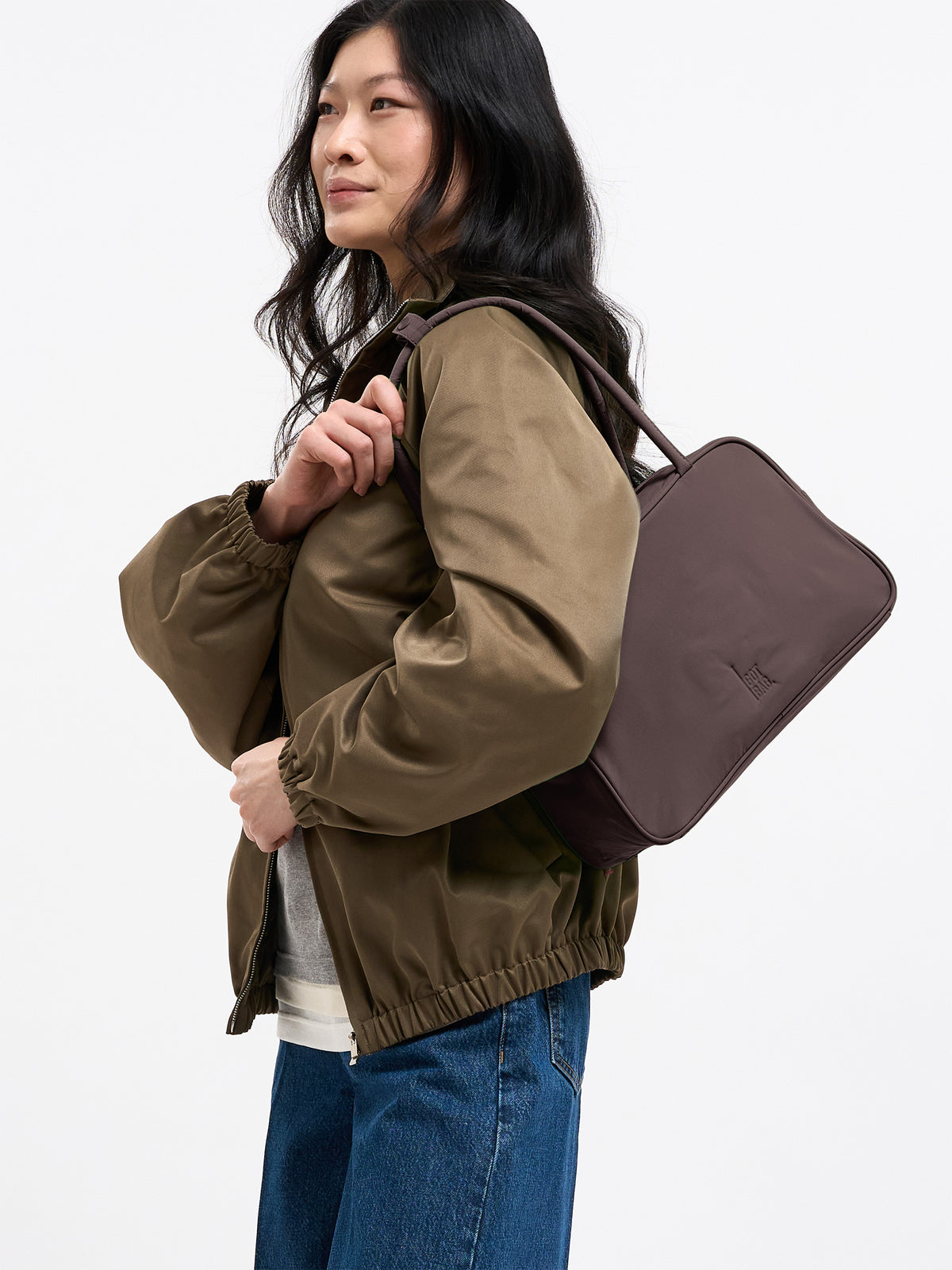STRIKE BAG Tasche in sea lion (dunkles Schokobraun) von einer Frau über der Schulter getragen.