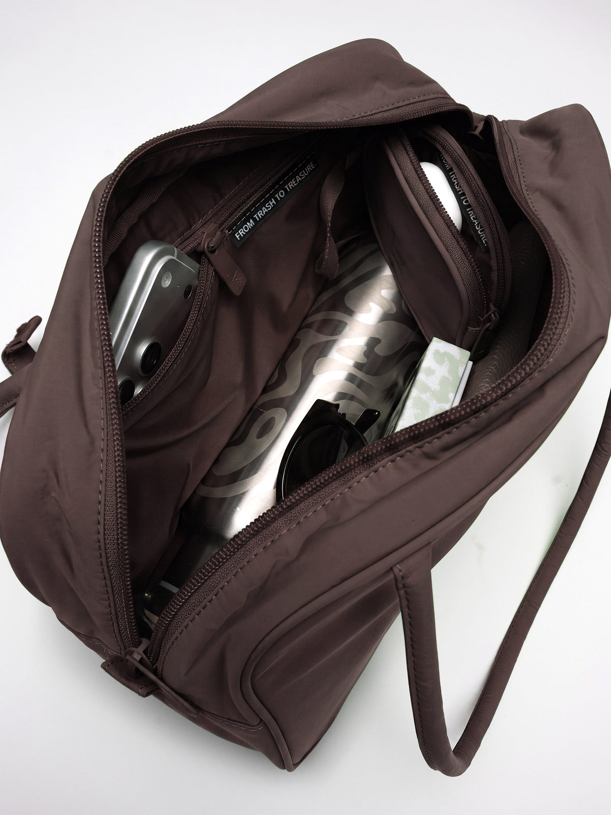 STRIKE BAG Tasche in sea lion (dunkles Schokobraun) mit Innenansicht und Inhalt.