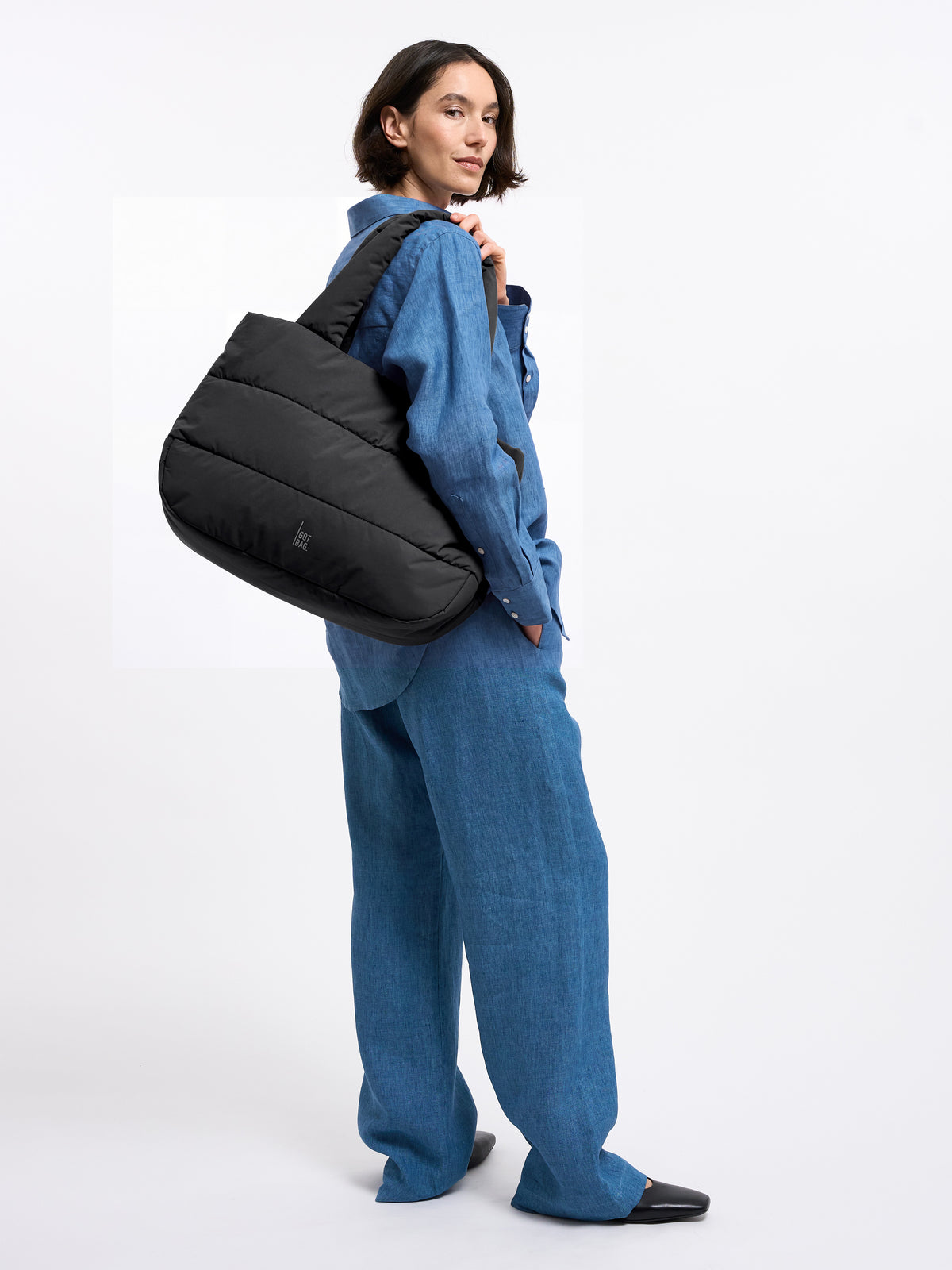 PUFFER HORIZON TOTE BAG Tasche in black (Schwarz) von einer Frau über der Schulter getragen.