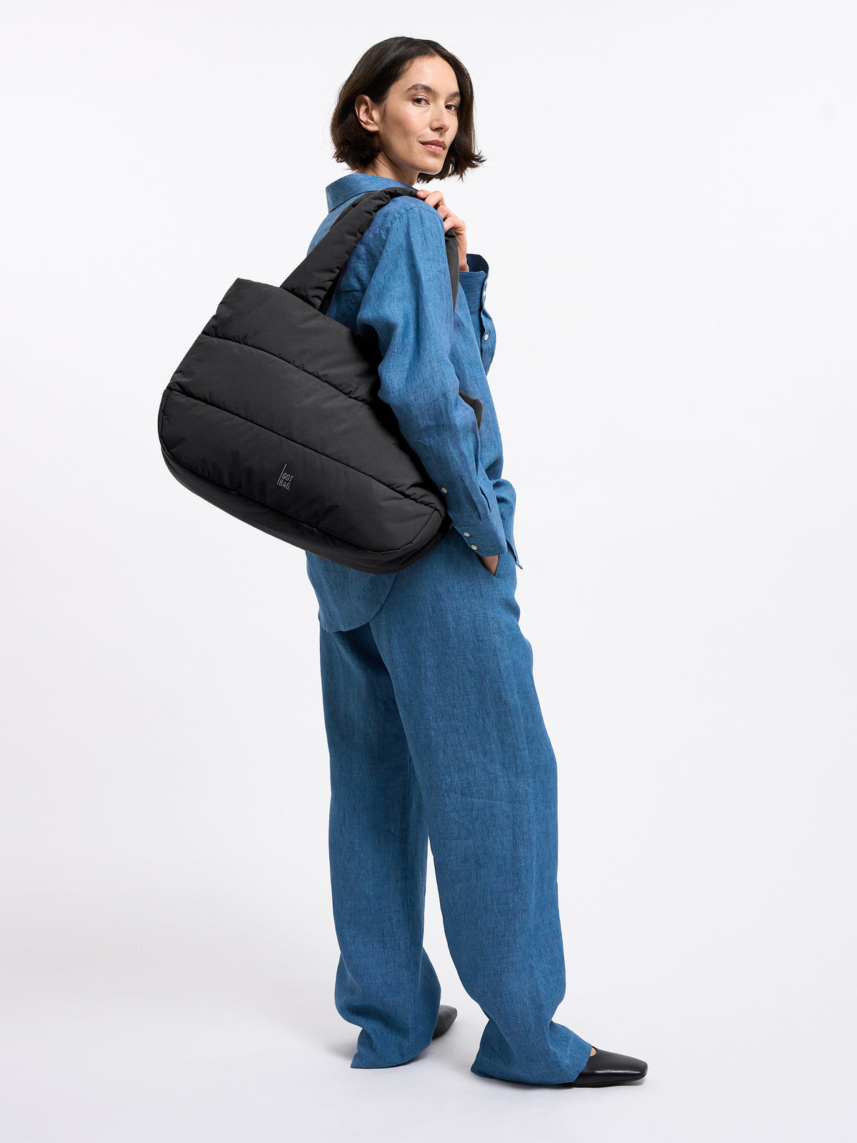 PUFFER HORIZON TOTE BAG Tasche in black (Schwarz) von einer Frau über der Schulter getragen.