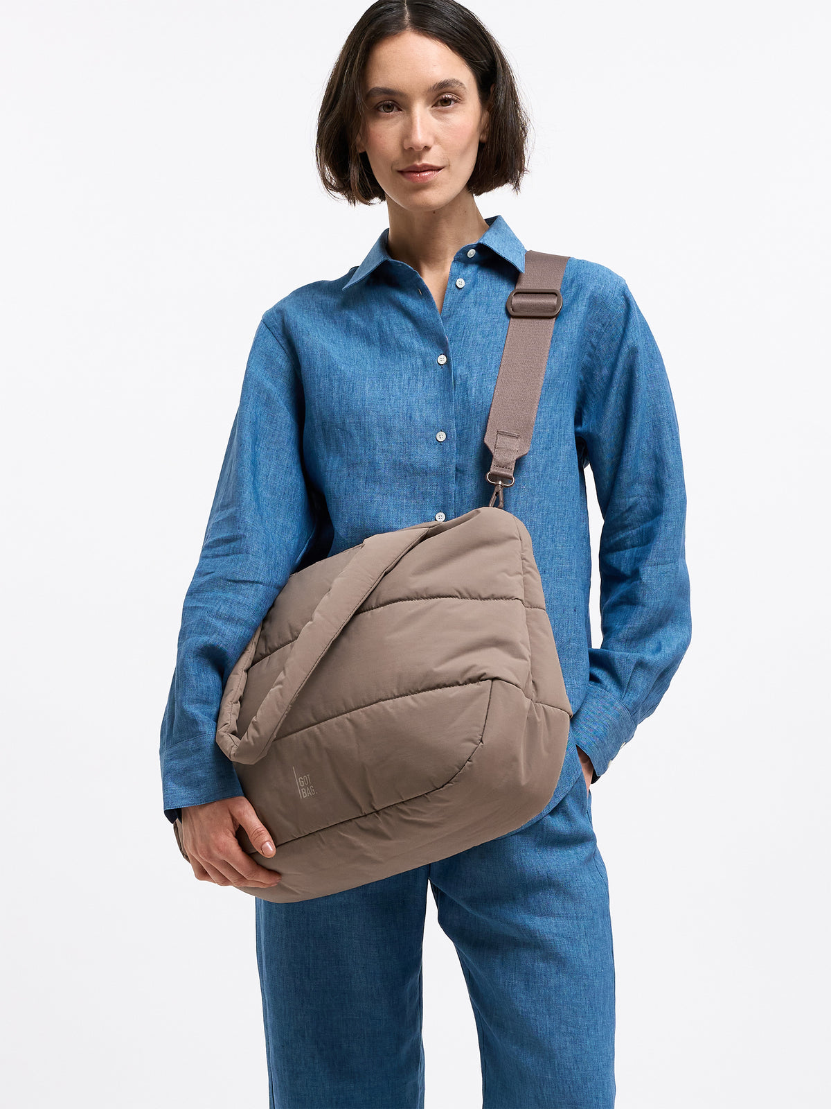 PUFFER HORIZON TOTE BAG Tasche in oyster (klassisches Taupe-Braun) von einer Frau über der Schulter getragen.