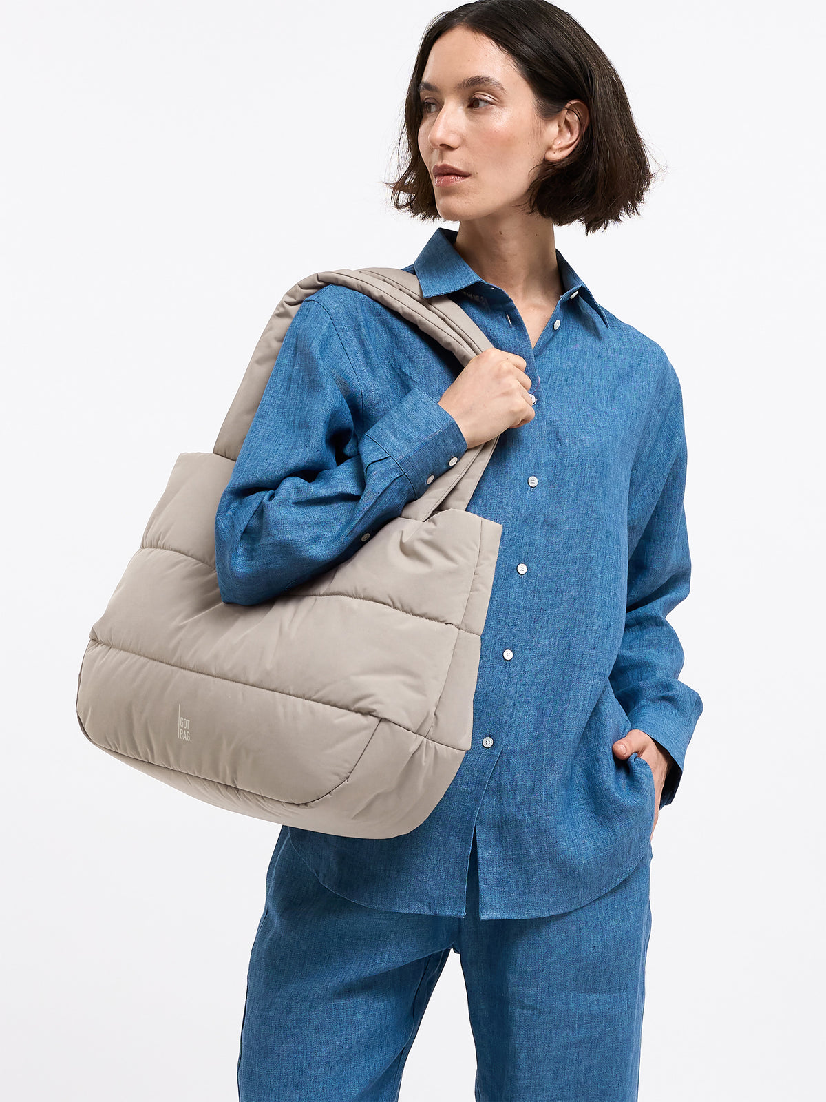PUFFER HORIZON TOTE BAG Tasche in scallop (helles Beige) von einer Frau über der Schulter getragen.