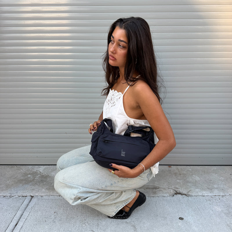 POCKET BAG SMALL bag in black (classic black) held in hand by a woman.