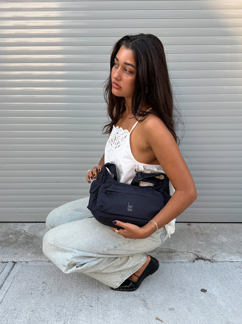 POCKET BAG SMALL bag in black (classic black) held in hands by a woman.