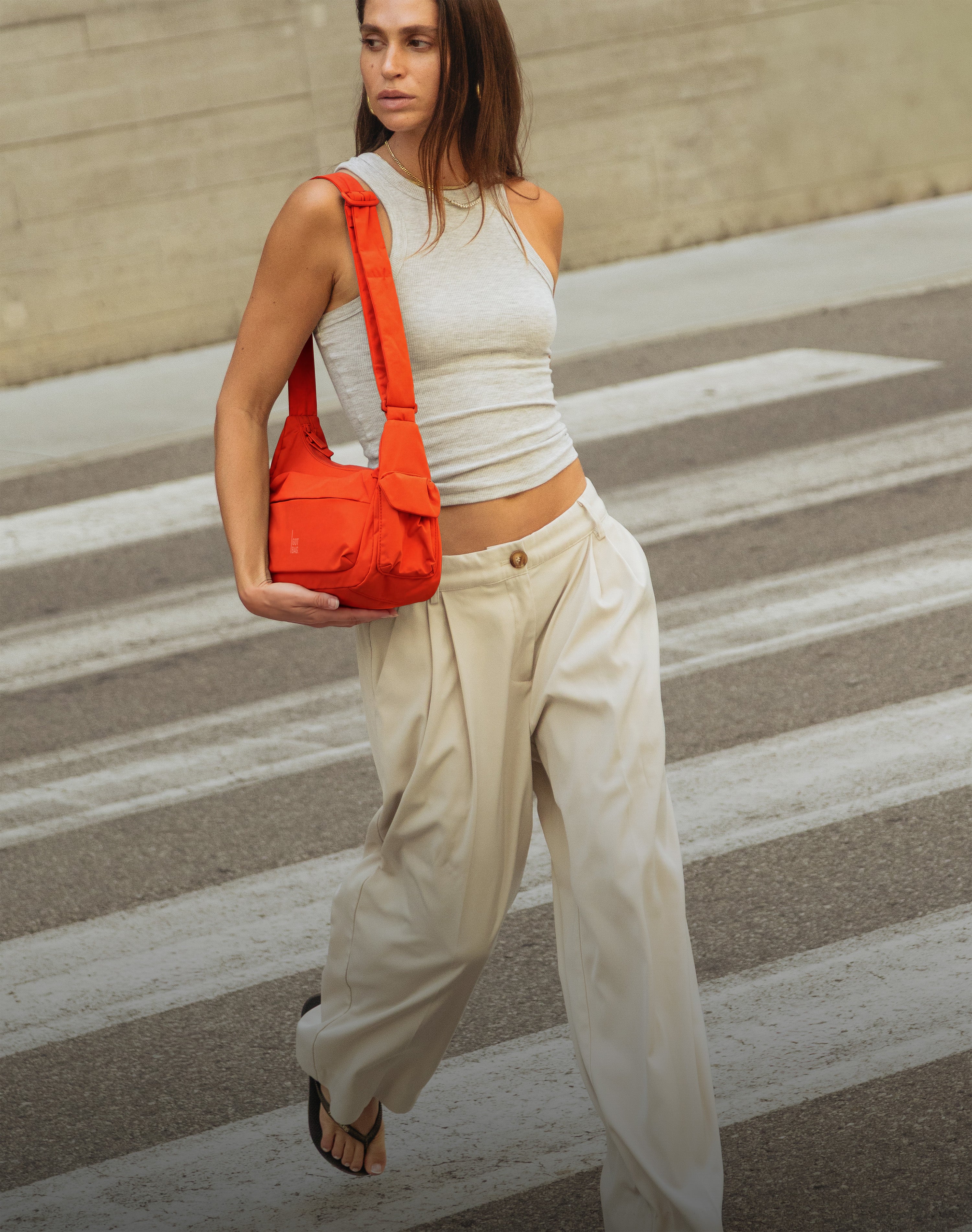 POCKET BAG SMALL bag in oyster (classic taupe-brown) carried over shoulder by a woman.