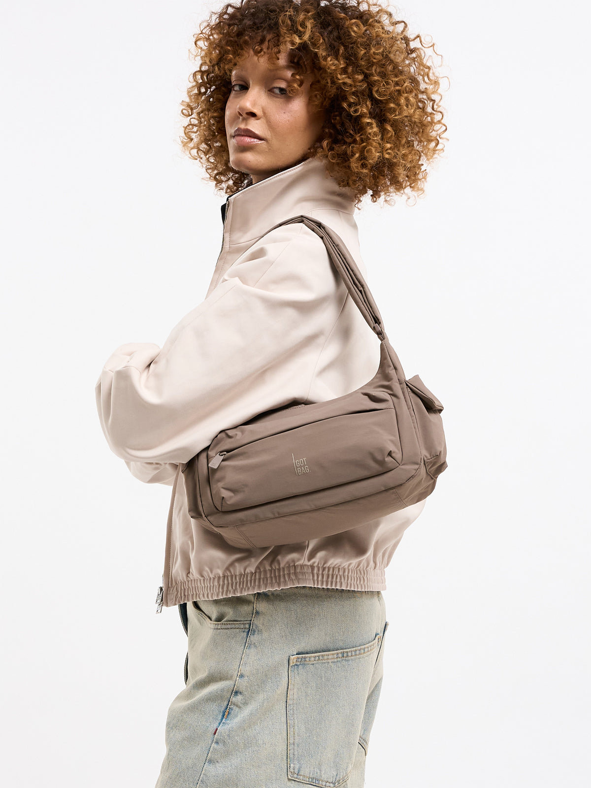 POCKET BAG SMALL Tasche in oyster (klassisches Taupe-Braun) von einer Frau über der Schulter getragen.