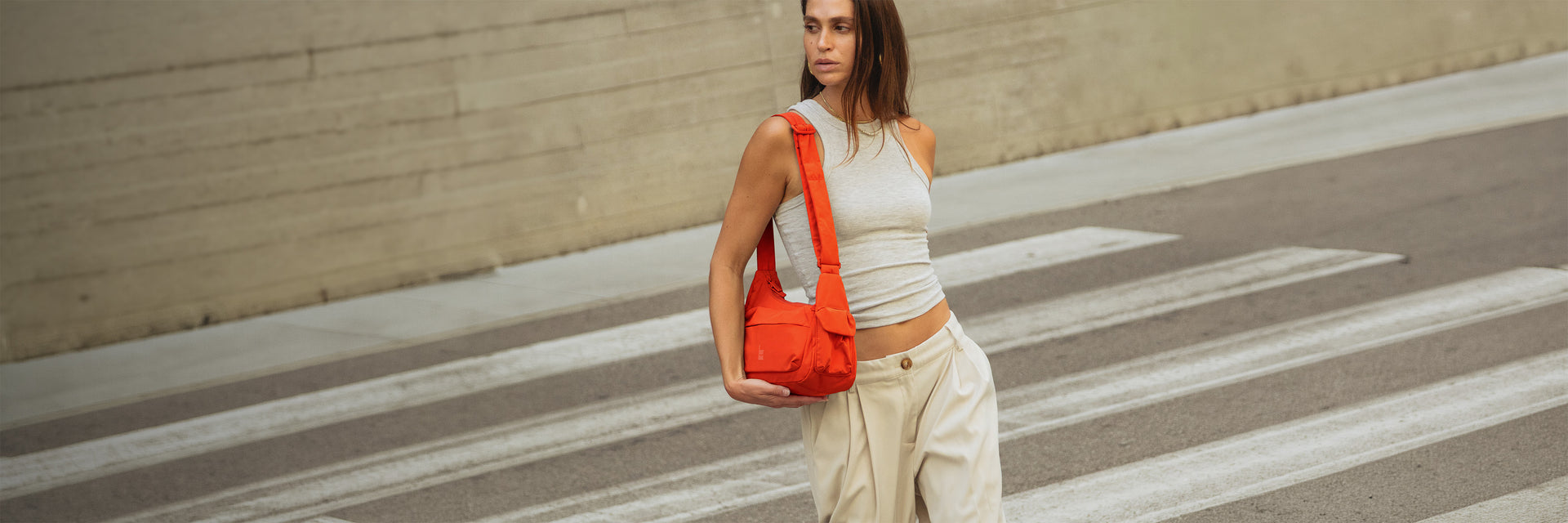 POCKET BAG SMALL bag in oyster (classic taupe-brown) carried over shoulder by a woman.
