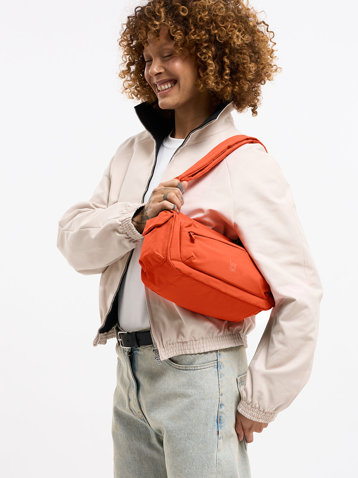 POCKET BAG SMALL Tasche in hot coral (knalliges Orange) von einer Frau über der Schulter getragen.
