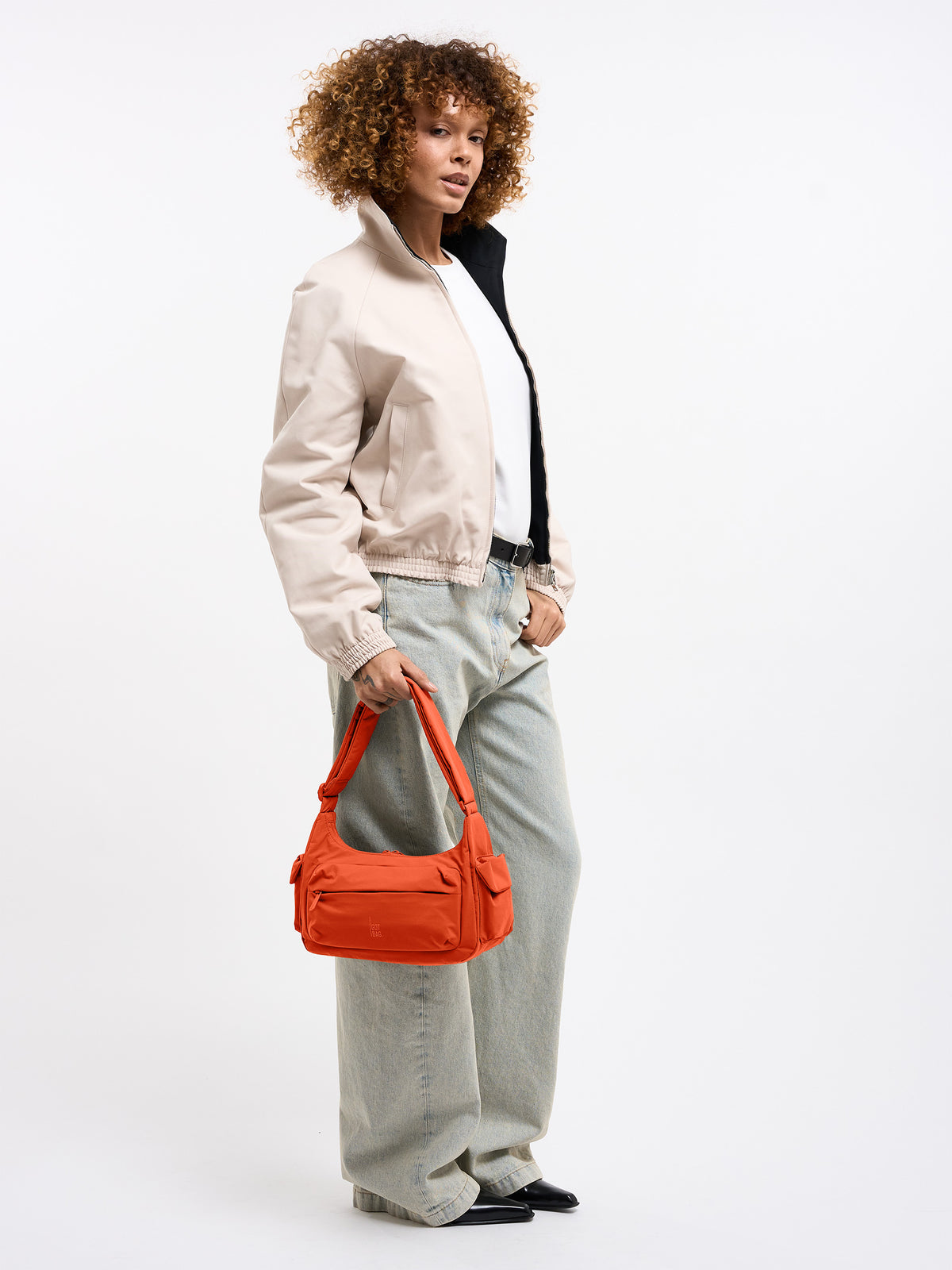 POCKET BAG SMALL Tasche in hot coral (knalliges Orange) von einer Frau in der Hand gehalten.
