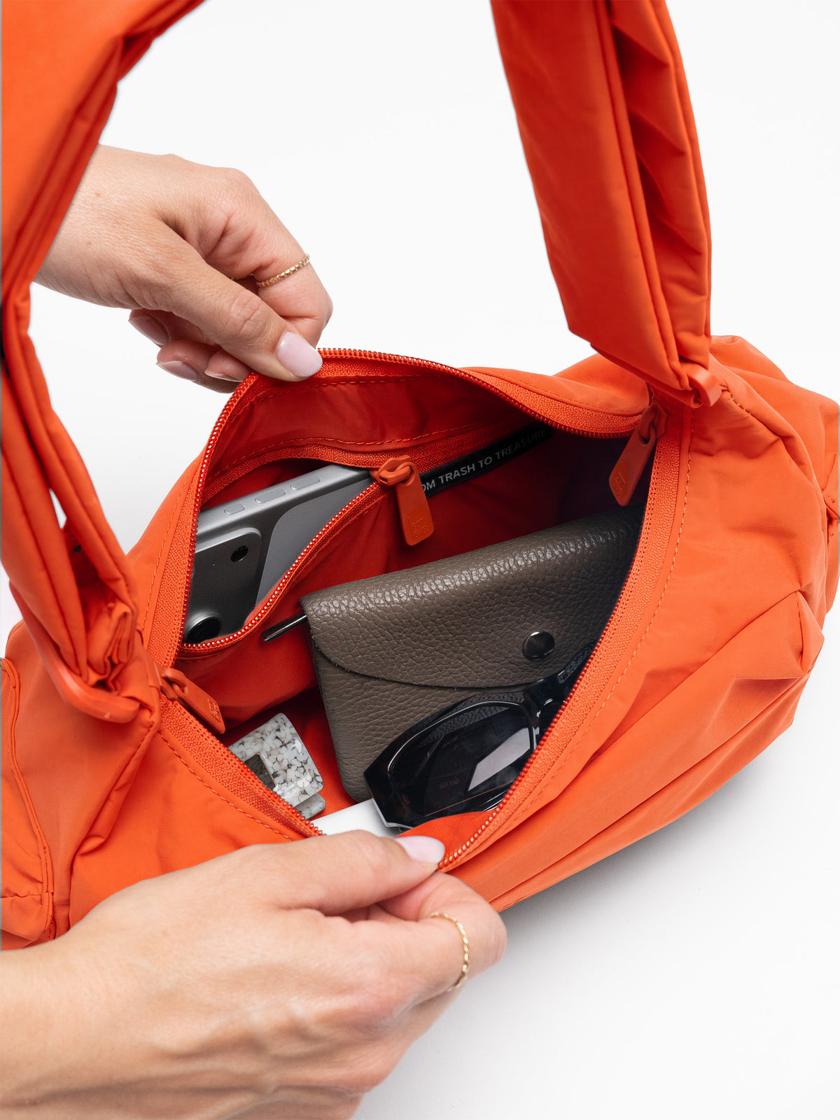 Innenansicht der POCKET BAG SMALL Tasche in hot coral (knalliges Orange), von einer Frau geöffnet.