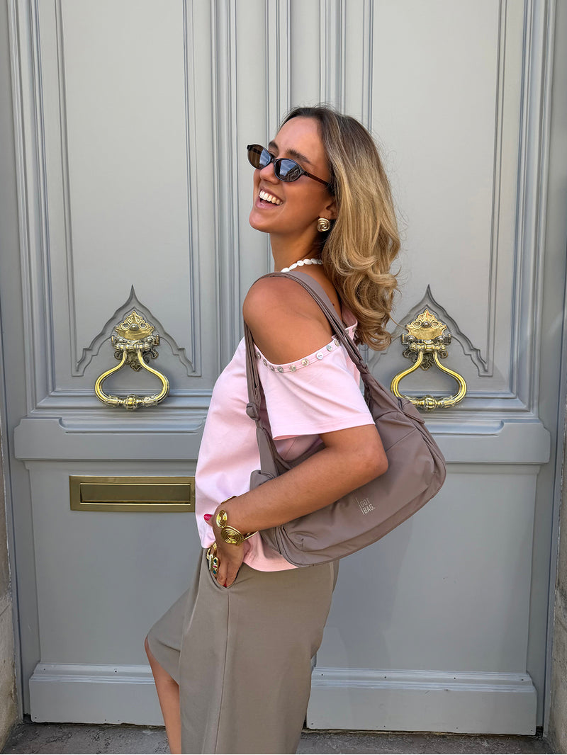 POCKET BAG SMALL bag in oyster (classic taupe-brown) worn over the shoulder by a woman.