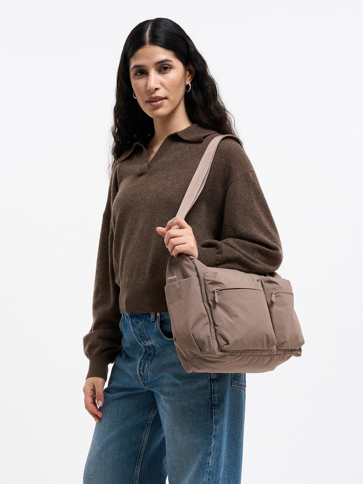 POCKET SLING BAG Tasche in oyster (klassisches Taupe-Braun) von einer Frau über der Schulter getragen.