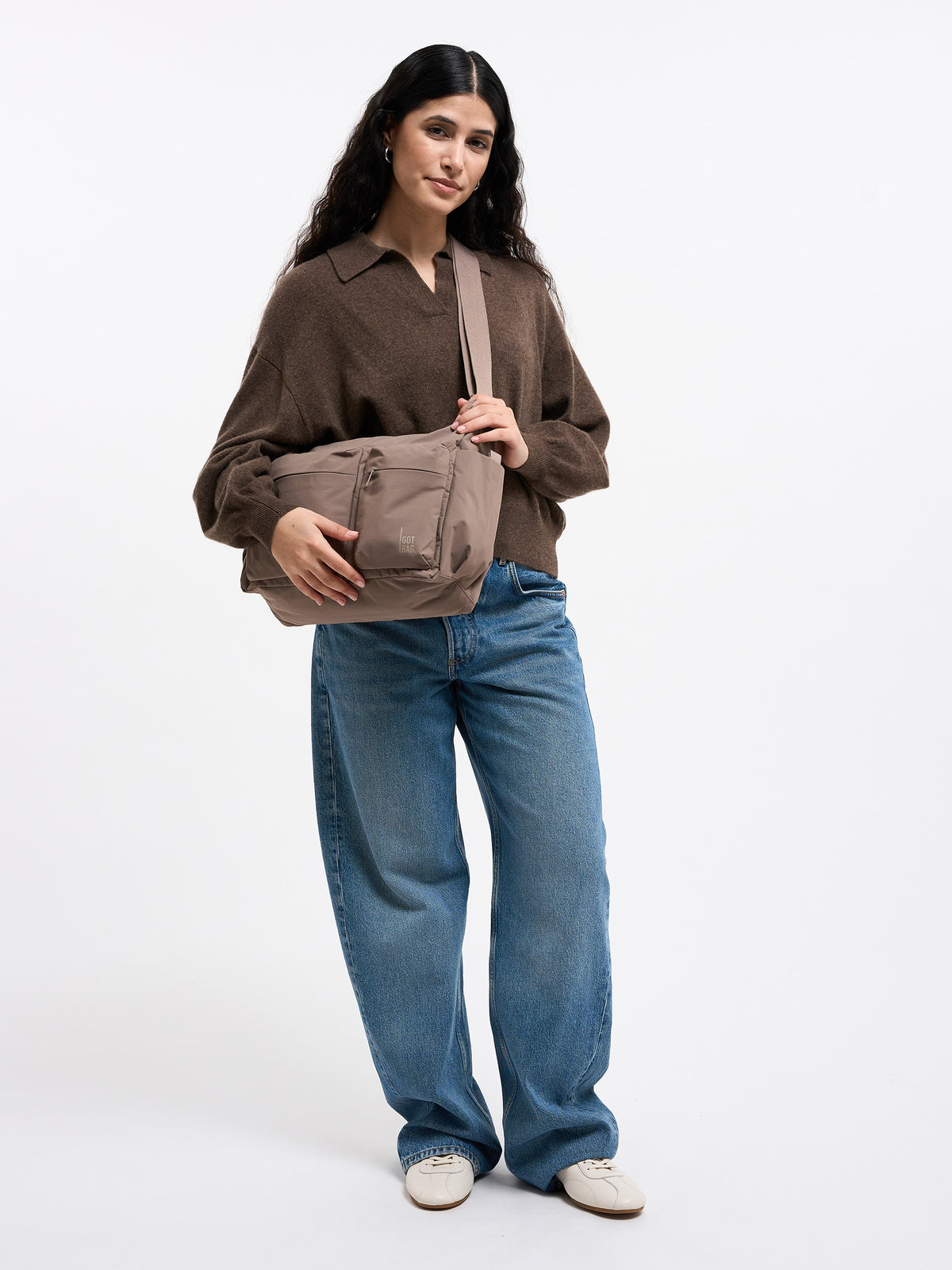 POCKET SLING BAG Tasche in oyster (klassisches Taupe-Braun) von einer Frau crossbody getragen.