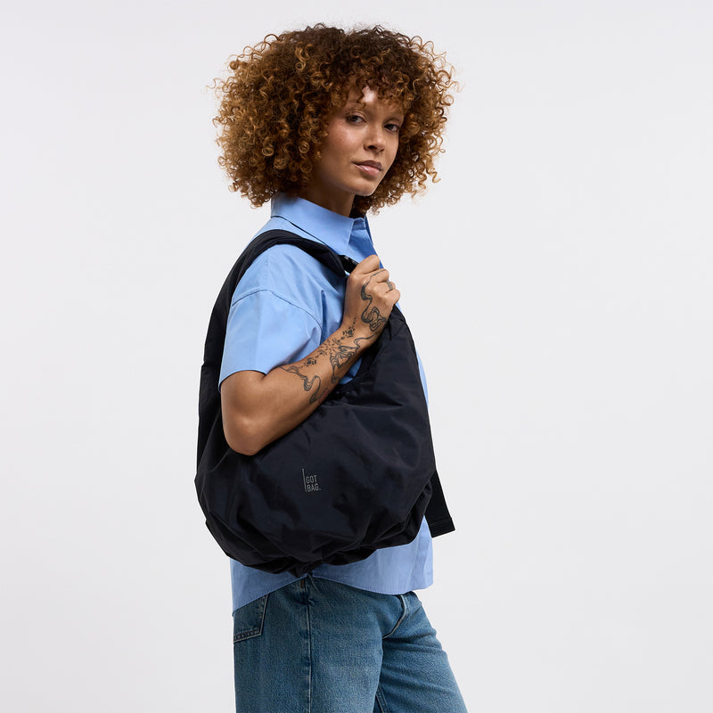 FULL MOON BAG Tasche in black (Schwarz) von einer Frau über der Schulter getragen.