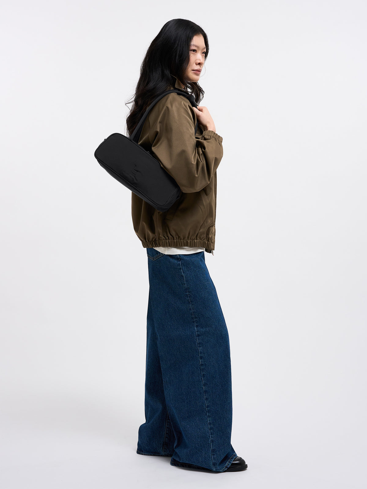 STRIKE BAG SMALL Tasche in black (Schwarz) von einer Frau über der Schulter getragen.