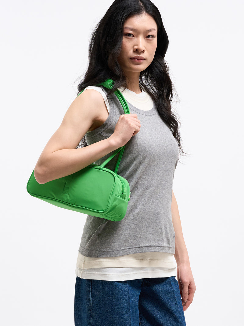 STRIKE BAG SMALL Tasche in leaf von einer Frau über der Schulter getragen.